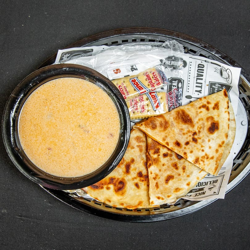 A bowl of creamy soup, folded flatbread, and crackers served in a basket.